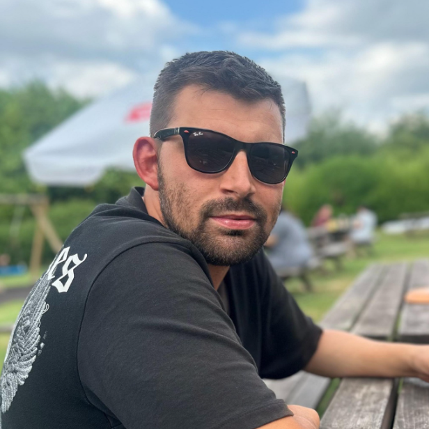Mac on track - Mike with sunglasses sitting at a picnic table in a park.