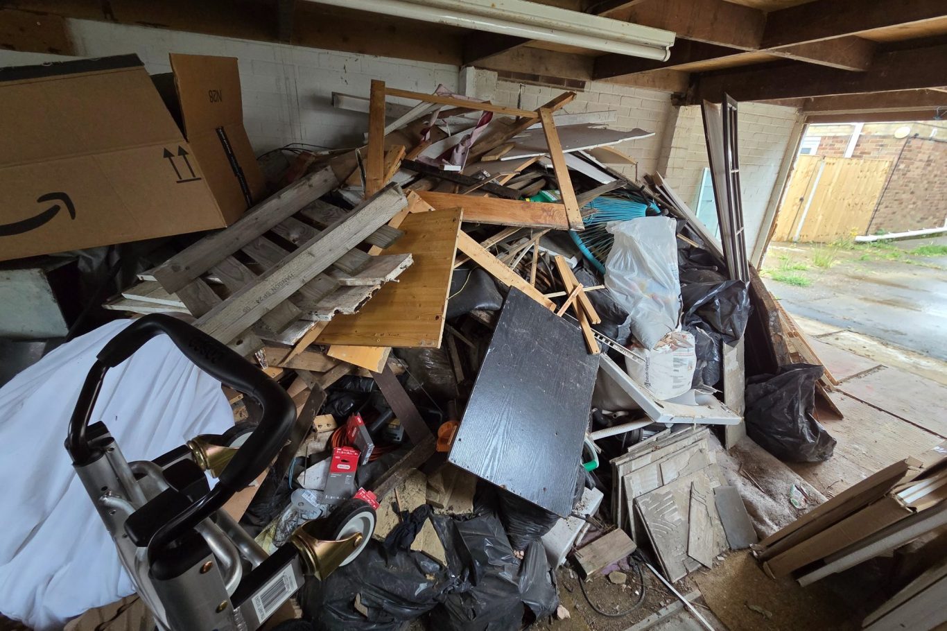 A cluttered indoor space filled with assorted piles of debris and discarded materials. A cluttered indoor space filled with assorted piles of debris and discarded materials.